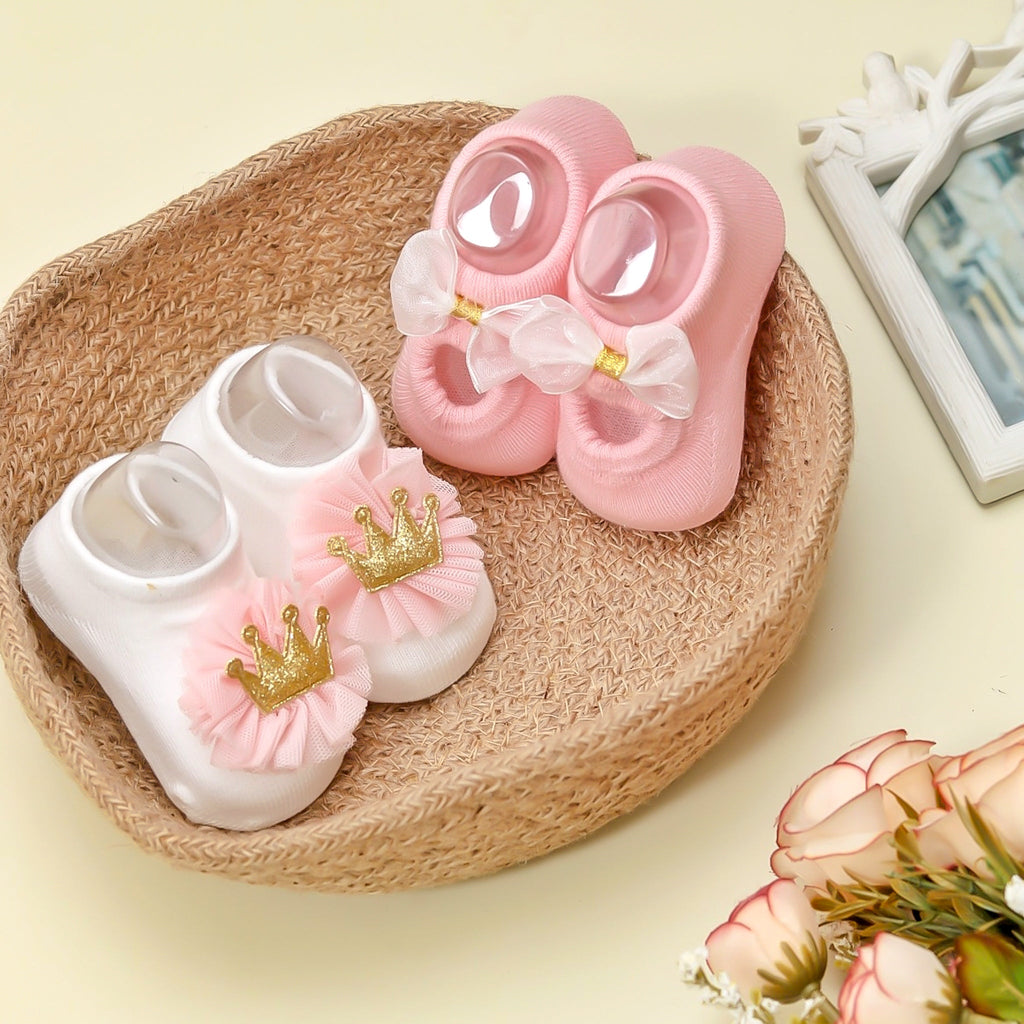 Baby girl's white and pink crown socks with golden detail on woven mat