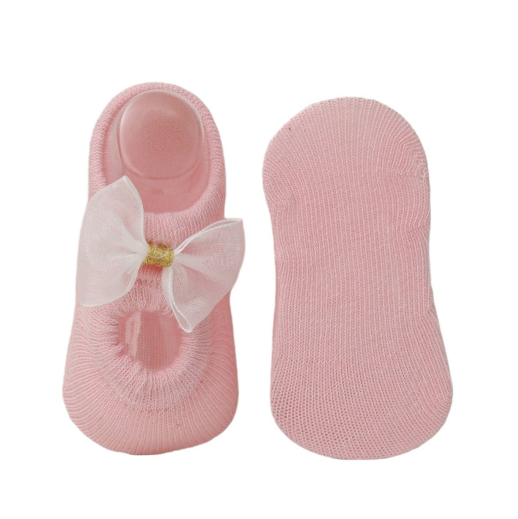Pink baby socks with bow, showing non-slip sole design.
