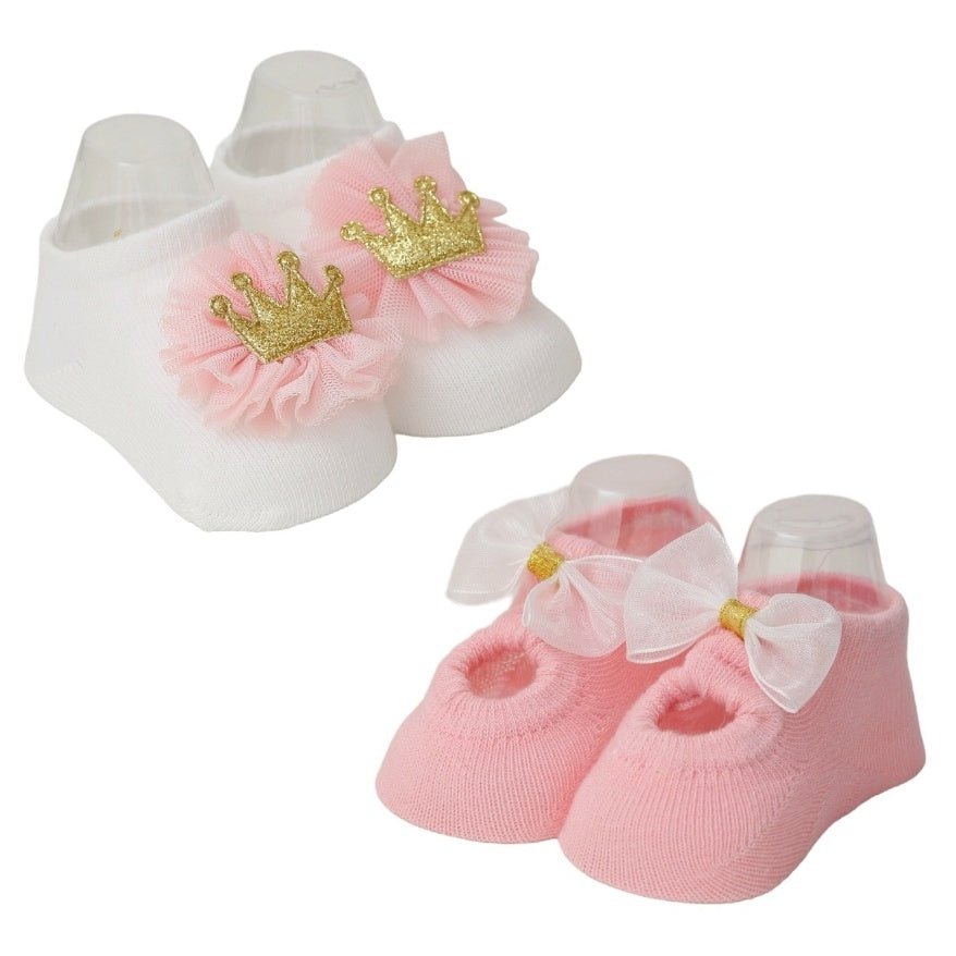 Pair of baby girl's crown and bow socks set against a cream background.