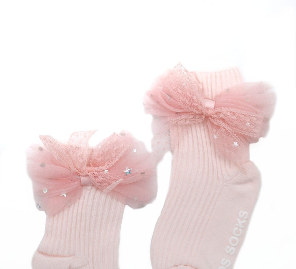 Close-up view of kid's pink sock featuring a sparkling tulle bow detail.