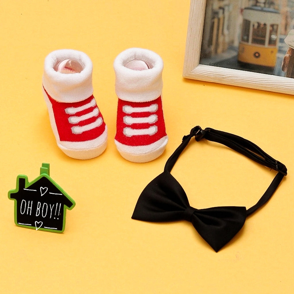 Infant's fashion set with red and black socks and bow-tie on a bright yellow background.