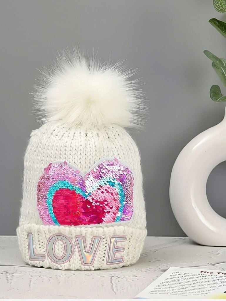 White woolen beanie for girls with a reversible sequin heart and pom-pom, showcasing LOVE lettering.