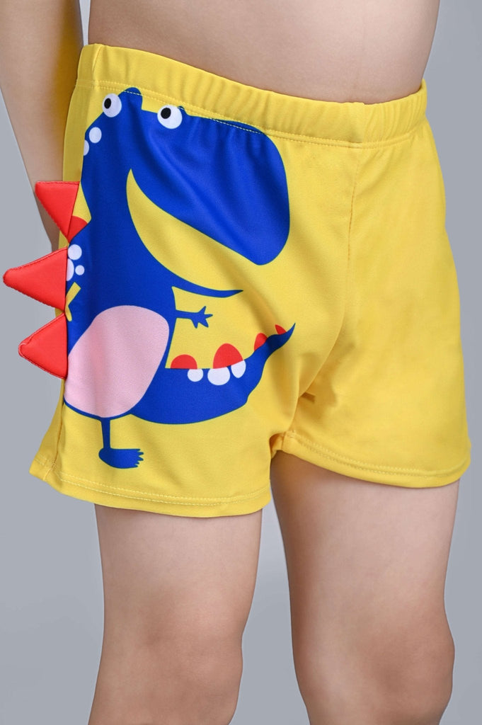Close-up side view highlighting the red fin detail on boys' yellow dinosaur swim shorts