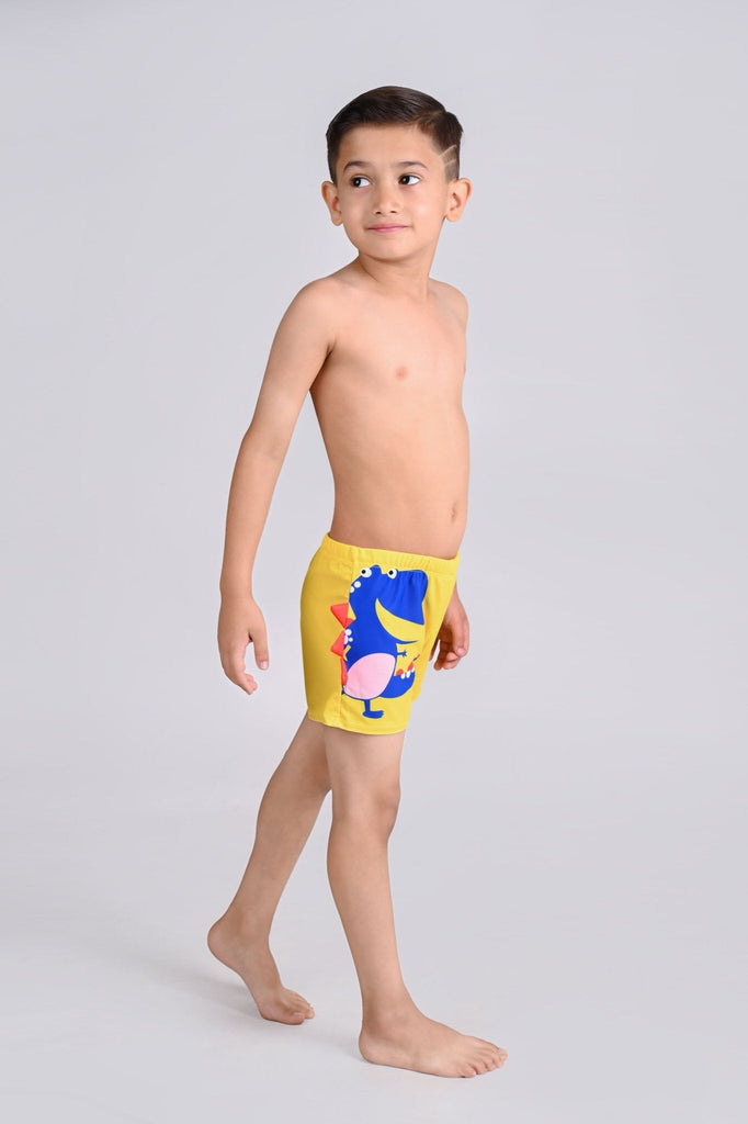 Boy standing side view showcasing the playful blue dinosaur design on yellow swim shorts