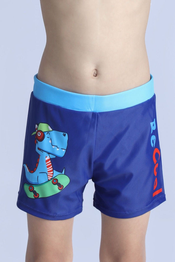 Close-up of skating dinosaur design on blue swim shorts with 'Be Cool' text.