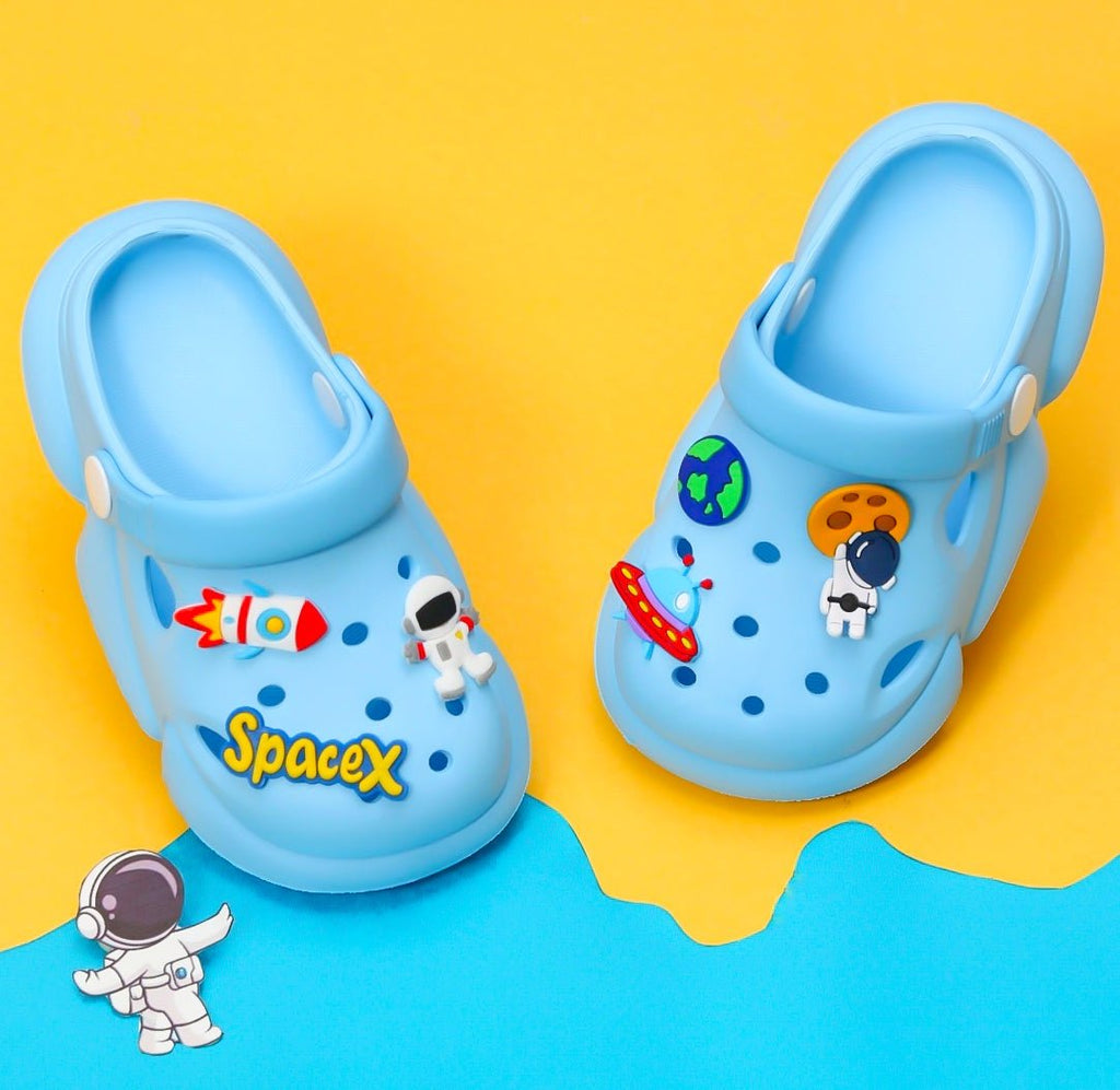 Blue toddler clogs with colorful space rocket and astronaut motifs on a yellow background