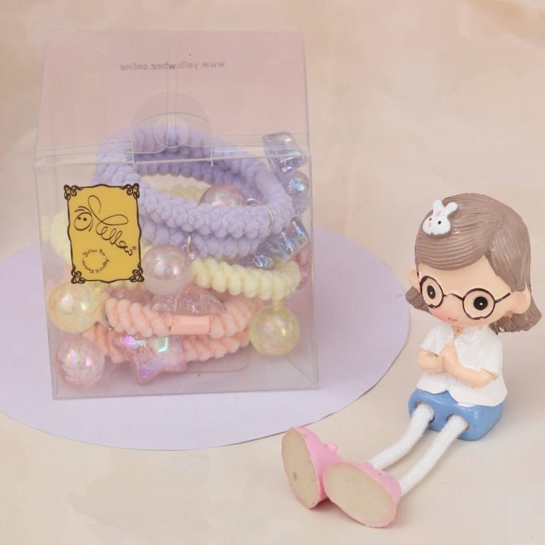 Yellow Bee's packaged soft braided hair ties with pendants, presented beside a cute figurine, perfect for gifting.