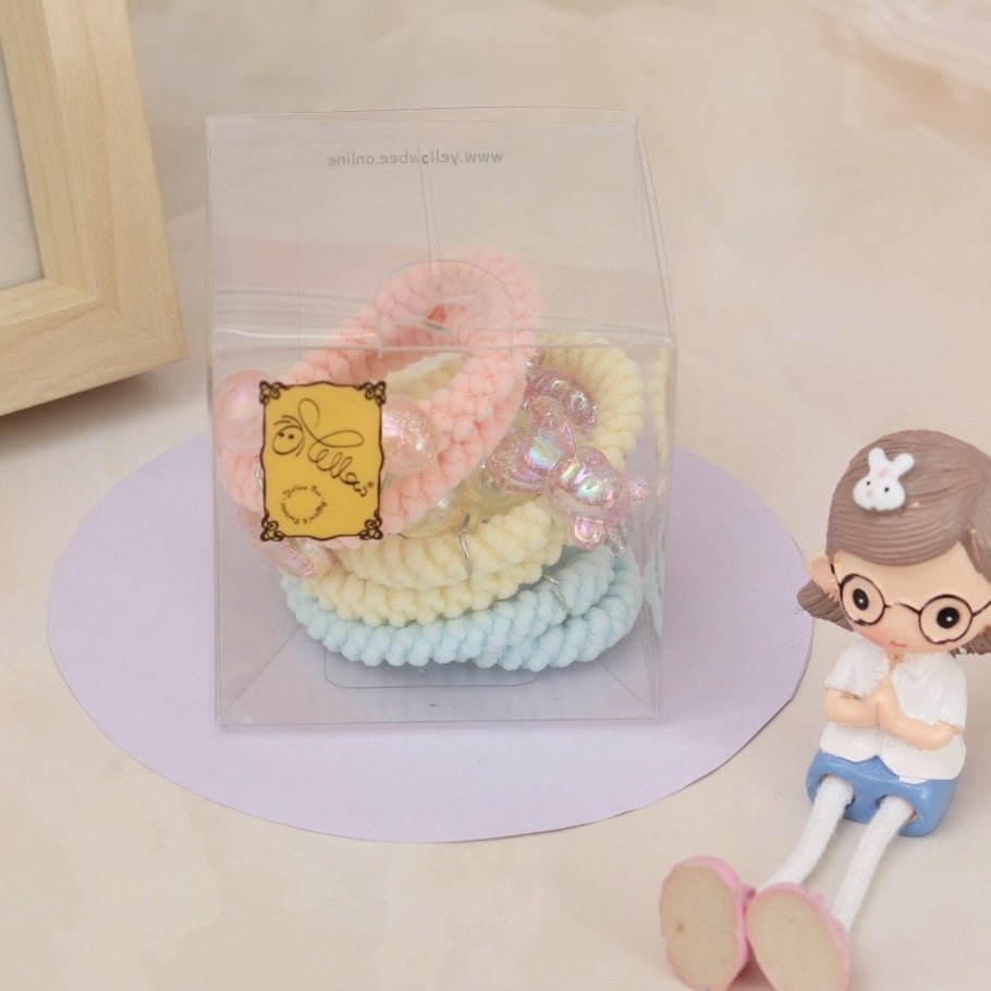 A set of soft, pastel-colored Yellow Bee braided rubber bands with shimmering pearls laid out on a Yellow backdrop.