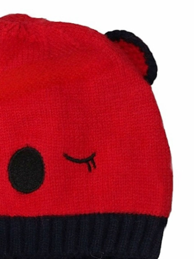 Close-up of a red knitted beanie with teddy ears detail for young boys.
