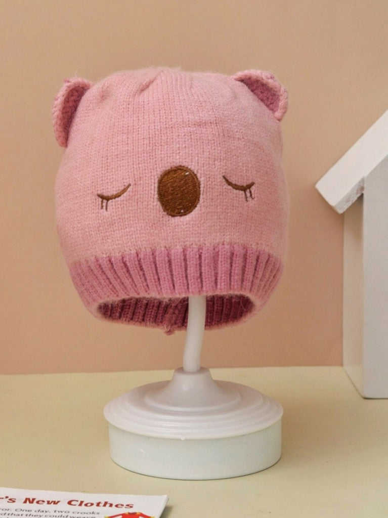 Light pink teddy ear knitted beanie for infant girls on a display stand.