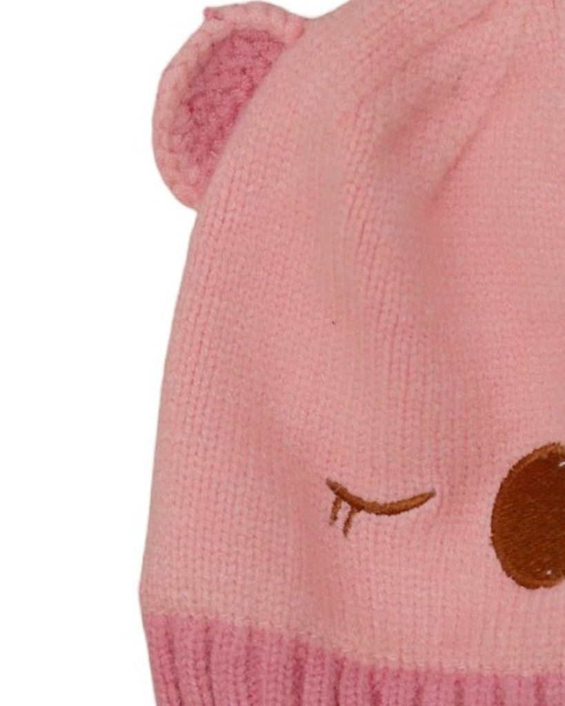 Light pink solid knitted beanie with teddy ears for girls laid flat.