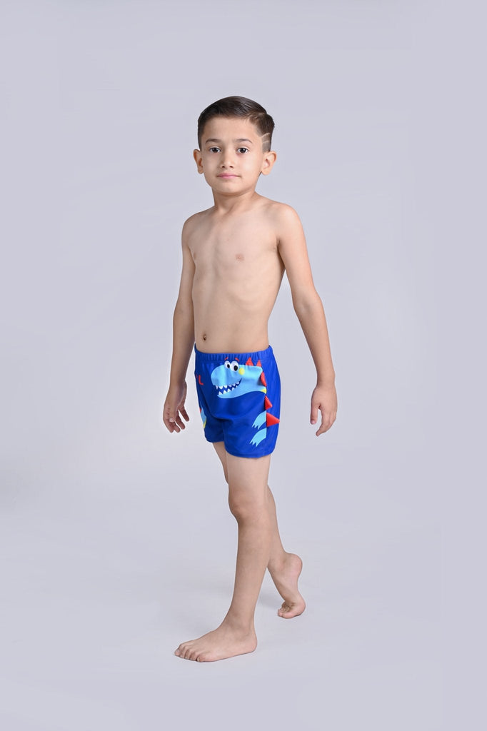 Full-length shot of a boy striking a pose in the blue dino swim shorts with vibrant red fin