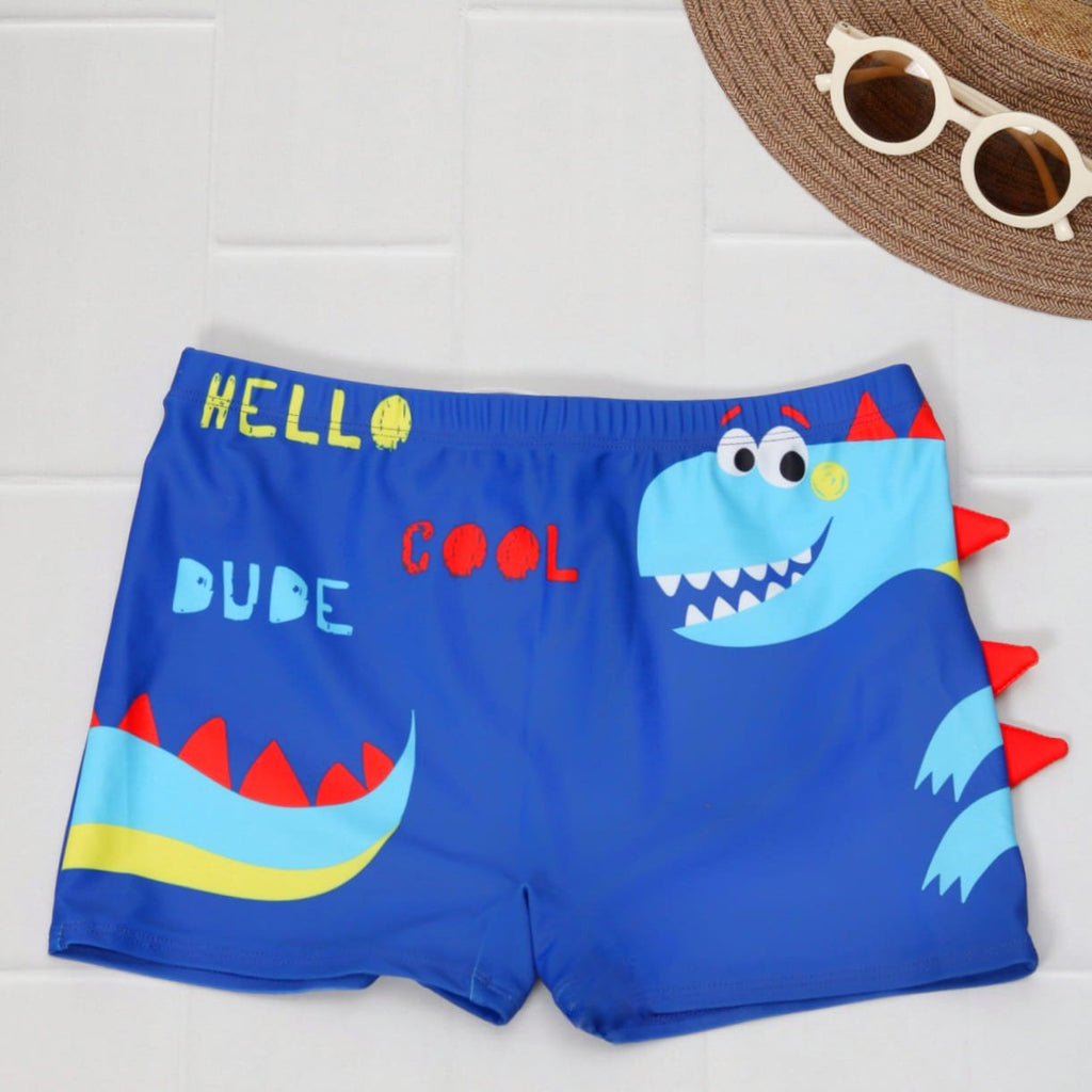 Blue swim shorts with 'HELLO DUDE COOL' text and fun dinosaur graphic for boys