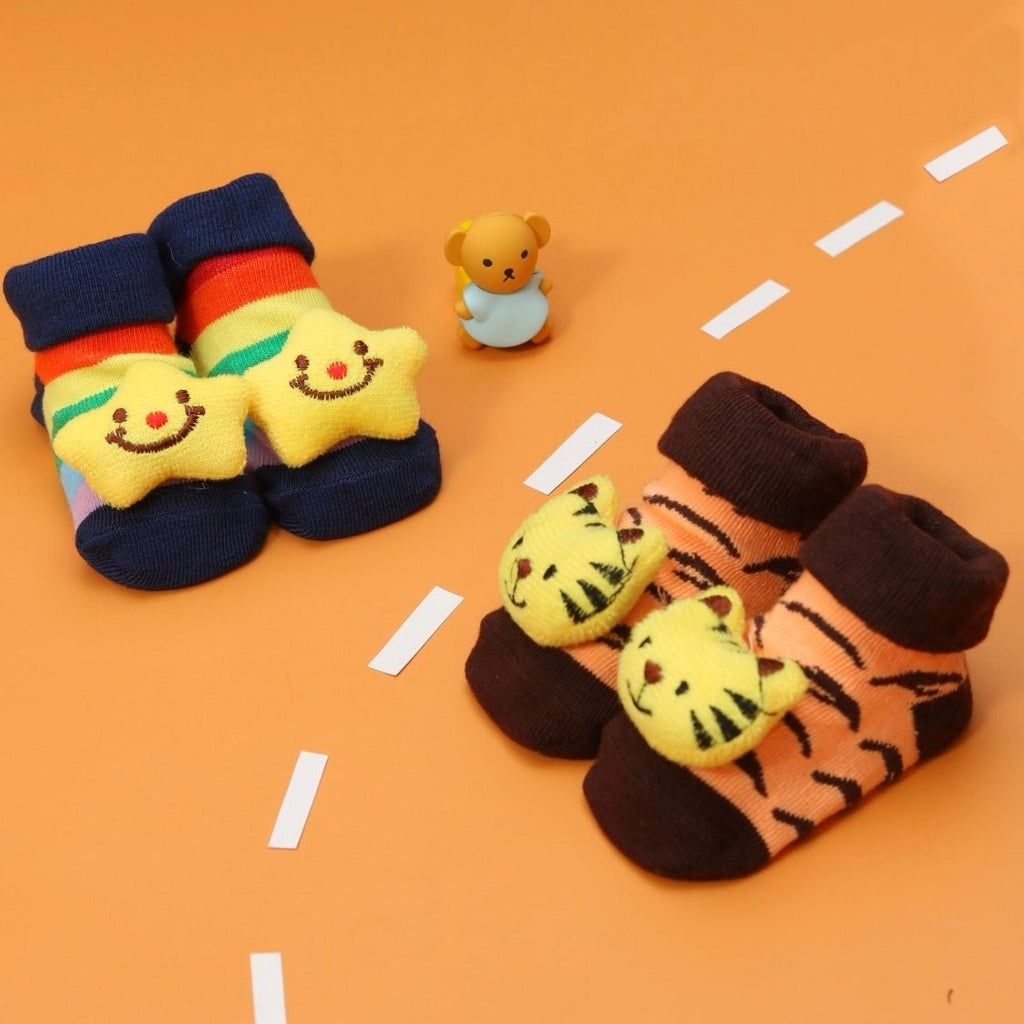 Two pairs of baby boy socks, one with stars and one with tiger patterns, on an orange background