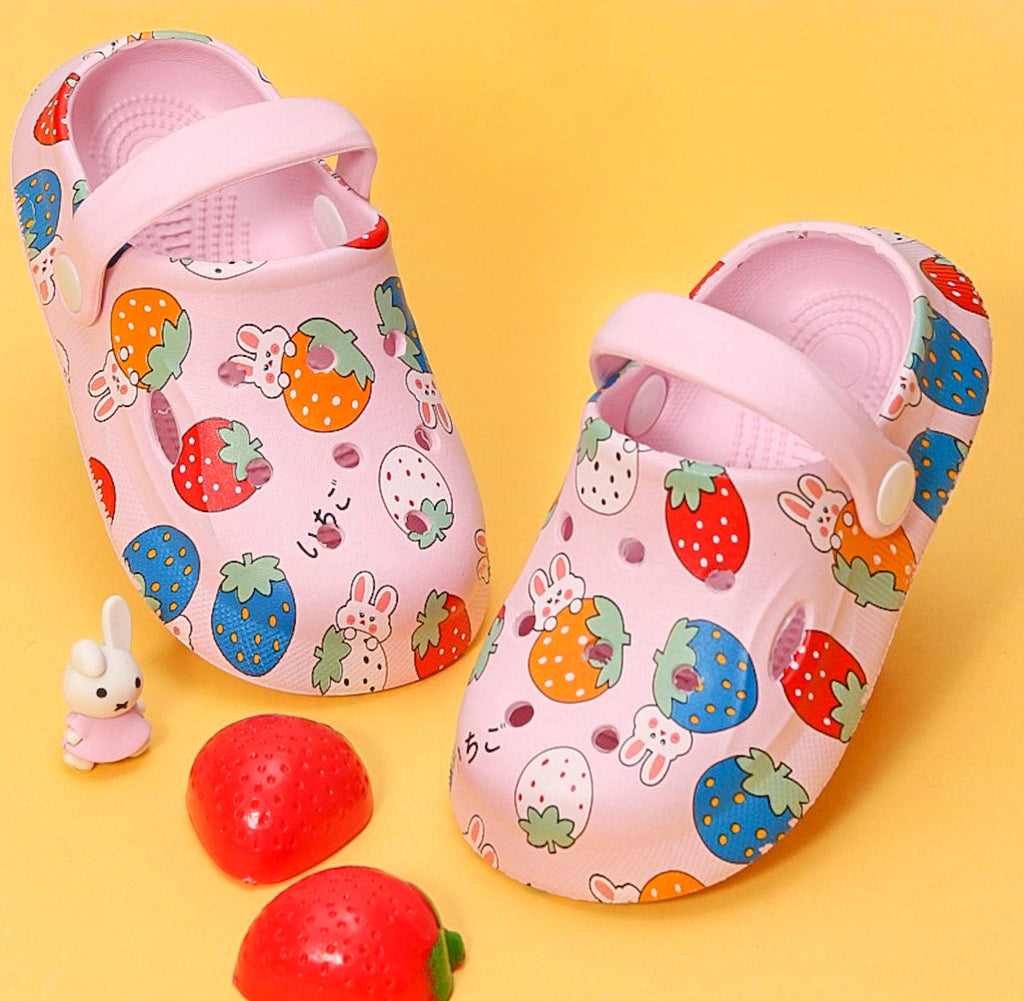 Adorable pink clogs for girls with bunny and strawberry print, accompanied by toy and strawberries on a yellow background