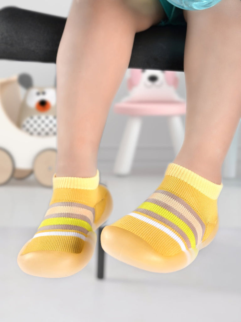 Cheerful child wearing Yellow Bee's yellow striped shoe socks with non-slip soles