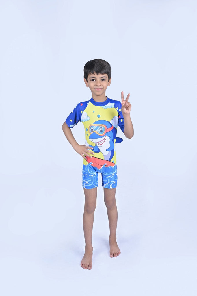 Young boy posing with a peace sign in the blue shark print half sleeve swimsuit