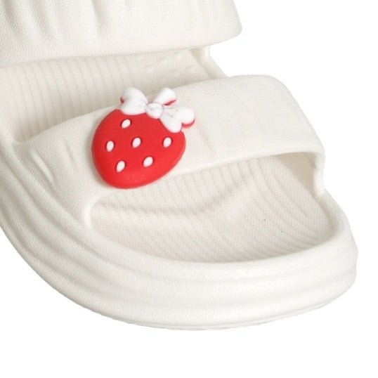 Zoomed-in view on the white sandals' toe strap with a red strawberry and bow detail."