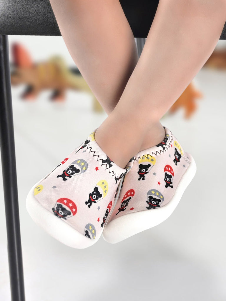 Child's feet in Yellow Bee sock shoes with teddy bear parachute design