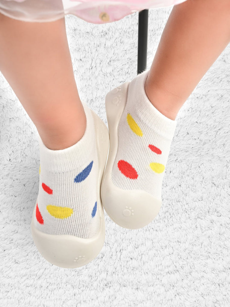 Frontal view of Yellow Bee's white polka dot shoe socks worn by a child, showcasing the playful design